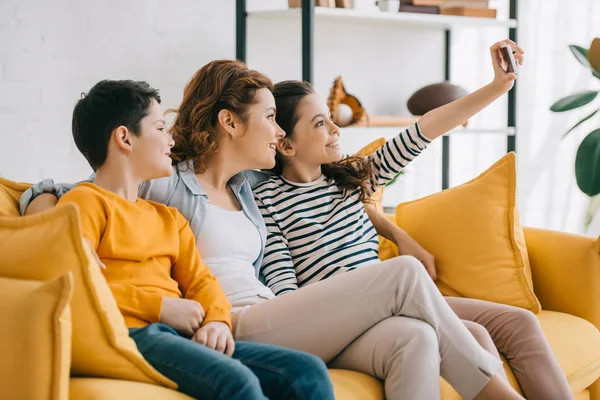Smiling Daughter Taking Selfie Mother Brother While Sitting Yellow Sofa — Stock Photo, Image