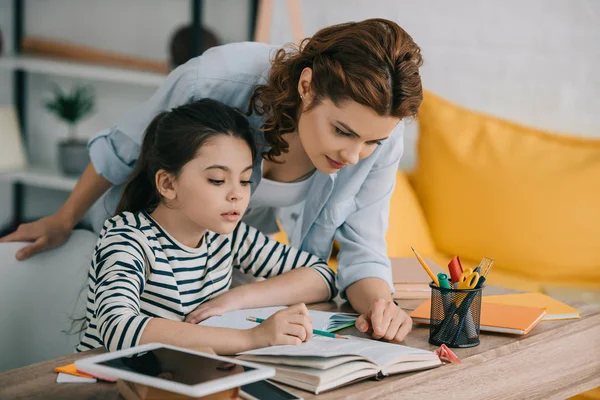 Atenta Madre Ayudando Adorable Hija Haciendo Trabajo Escolar Casa —  Fotos de Stock