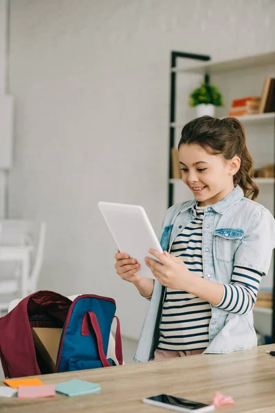 Bedårande Leende Kid Innehar Digital Tablett Stående Nära Skrivbordet Hemma — Stockfoto