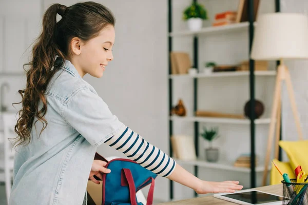 Cute Schoolchild Packing Back Pack While Standing Desk Digital Tablet — Stock Photo, Image