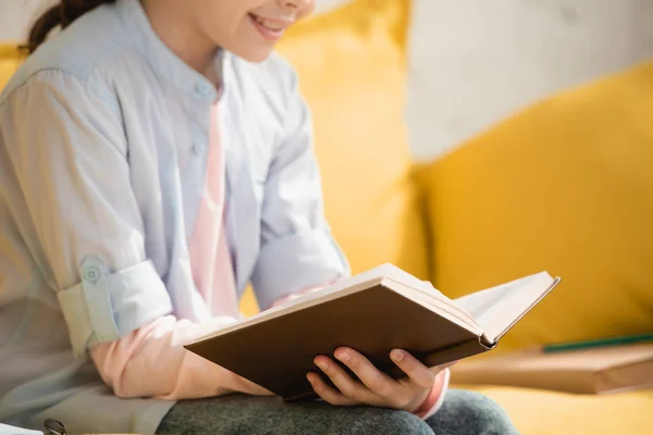 Vista Cortada Livro Leitura Criança Sorridente Enquanto Sentado Sofá Casa — Fotografia de Stock