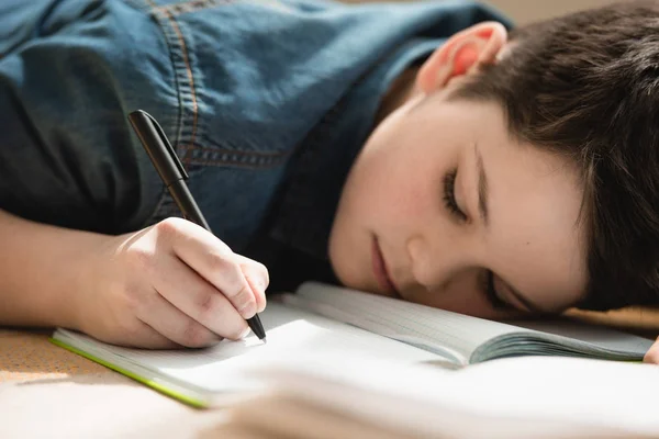 Ragazzo Esausto Sdraiato Sul Pavimento Scrivere Copia Libro Mentre Compiti — Foto Stock