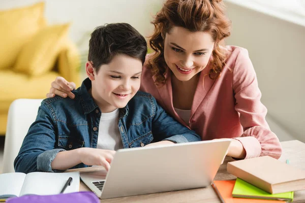 Happy Mother Omfamna Bedårande Son Medan Använder Laptop Tillsammans — Stockfoto
