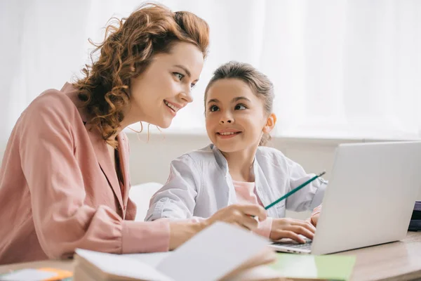 Happy Mother Pointing Laptop Screen While Helping Daughter Doing Homework — Stock Photo, Image