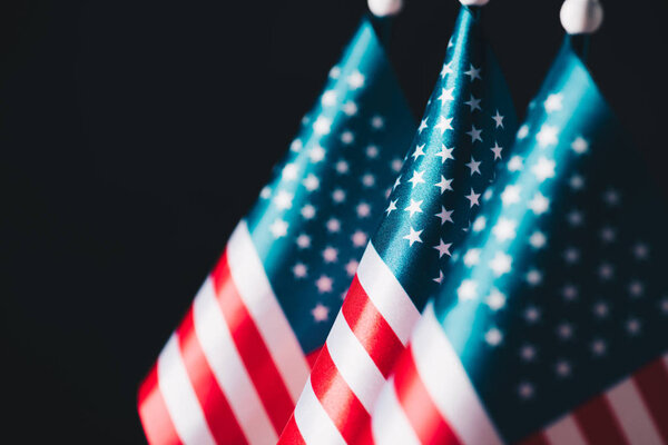 selective focus of usa national flags on flagpoles isolated on black, memorial day concept