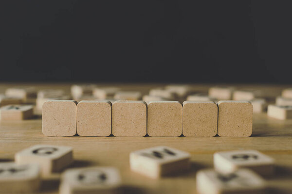 selective focus of six blank cubes surrounded by blocks with letters on wooden surface isolated on black