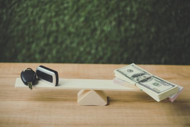 yeşil arka plan üzerinde salıncak üzerinde dolar banknotlar ve araba anahtarı dengeleme paketi