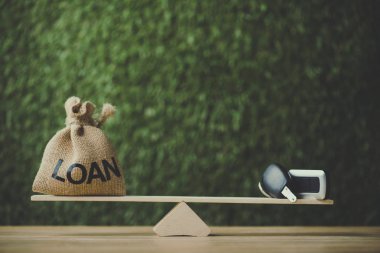 yeşil arka plan üzerinde tahterevalli üzerinde kredi yazıt ve araba anahtarı dengeleme ile para çantası