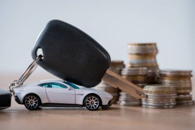 gri izole ahşap yüzey üzerinde minyatür araba, araba anahtarları ve metal sikkeler