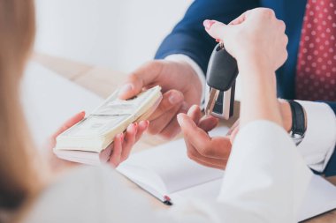 araba satıcısına para verirken araba anahtarları tutan kadının kısmi görünümü