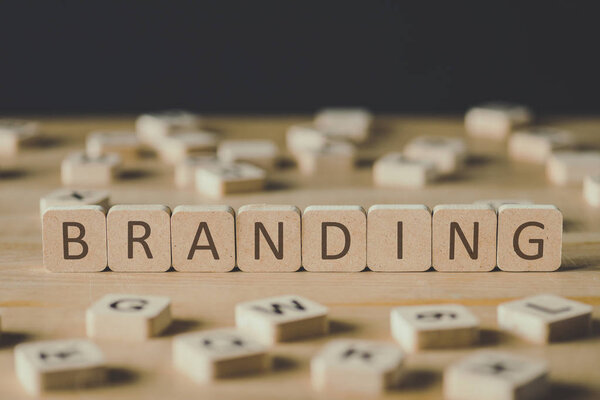 selective focus of branding lettering on cubes surrounded by blocks with letters on wooden surface isolated on black