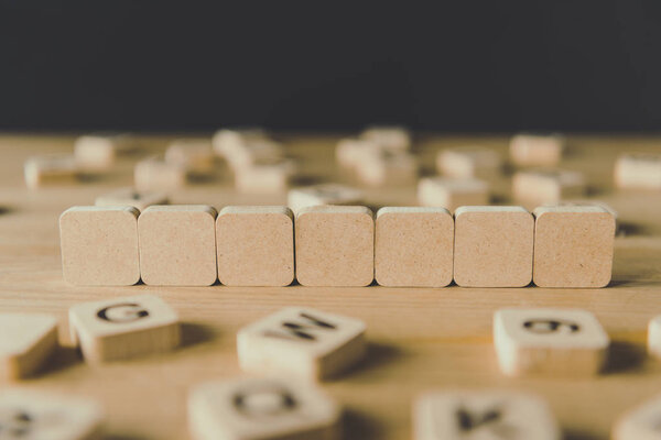 selective focus of seven blank cubes surrounded by blocks with letters isolated on black