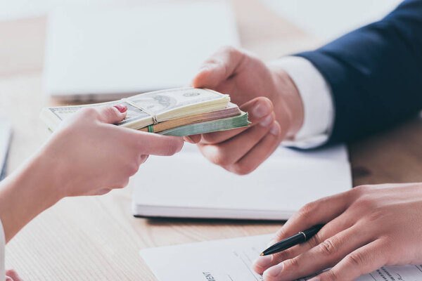 cropped shot of manager taking money from customer in office