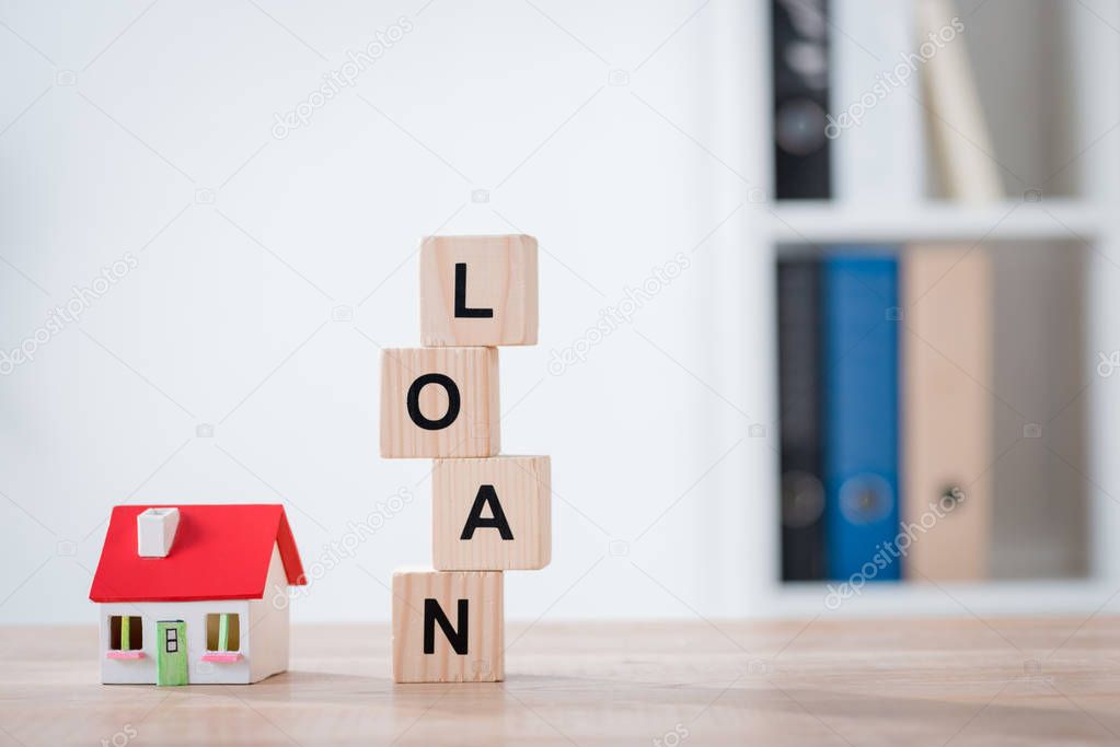 word loan made of wooden cubes and house model on wooden tabletop surface