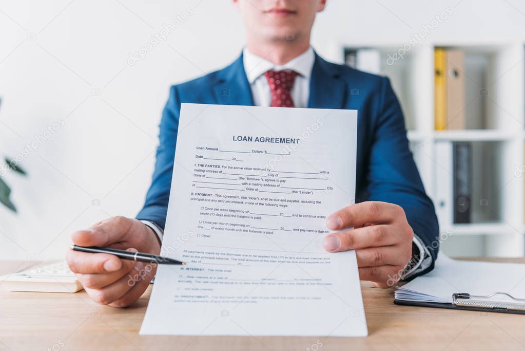 cropped view of manager pointing with pen at loan agreement