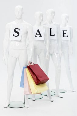 gri kağıtlar ve alışveriş çantaları üzerinde satış yazı ile mankenler