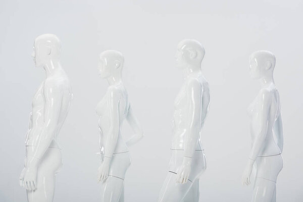 белые пластиковые манекены в ряд изолированы на сером
 