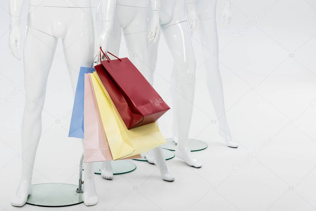 white mannequins with shopping bags isolated on grey