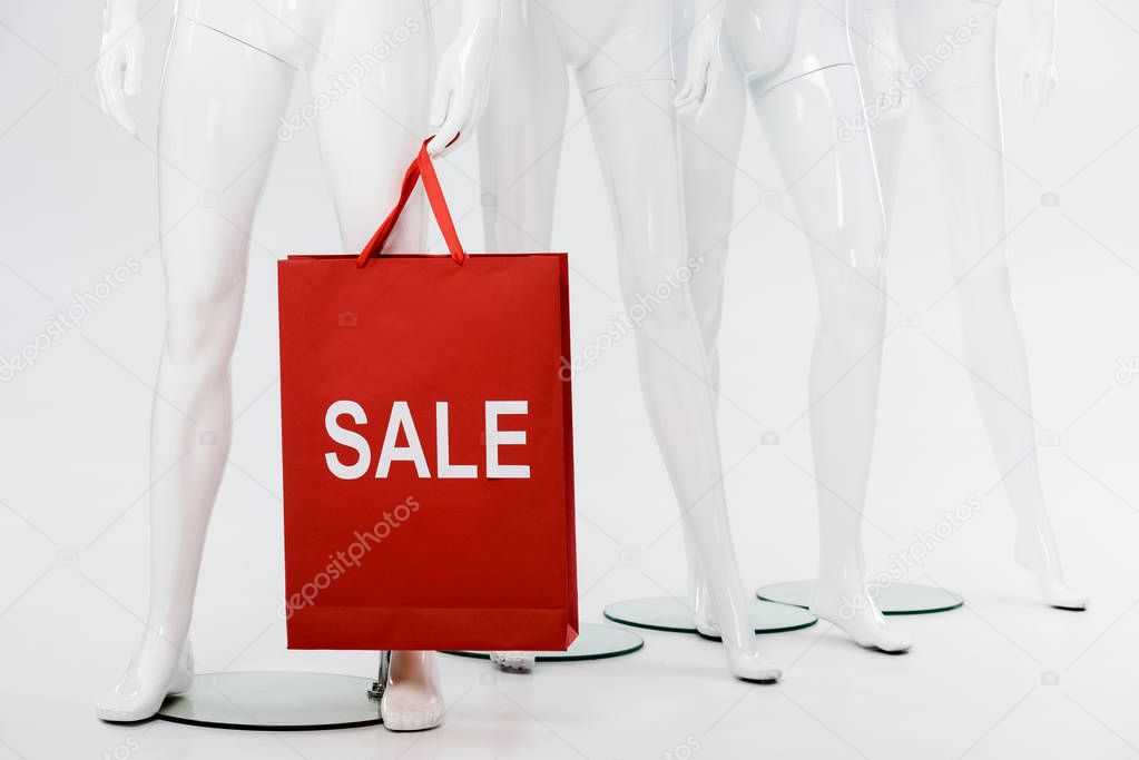 white mannequins and shopping bag with sale lettering on grey