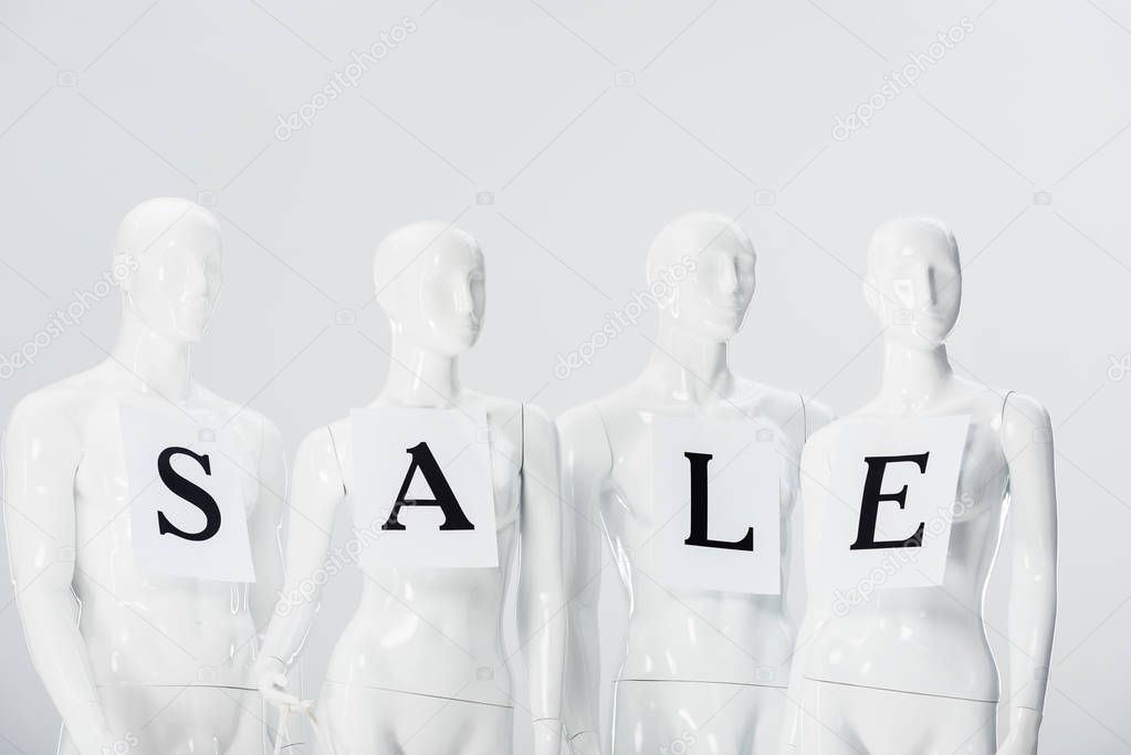 papers with sale lettering on white mannequins isolated on grey