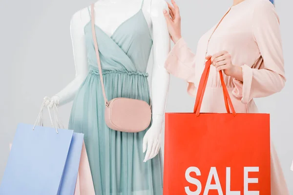年轻女子拿着购物袋 卖字在灰色上隔离的人体模型 — 图库照片