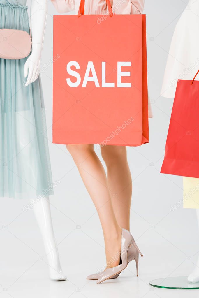 cropped view of young woman with shopping bag with word sale on grey