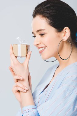 güzel şık kız hediye kutusu tutan ve gri izole gülümseyerek