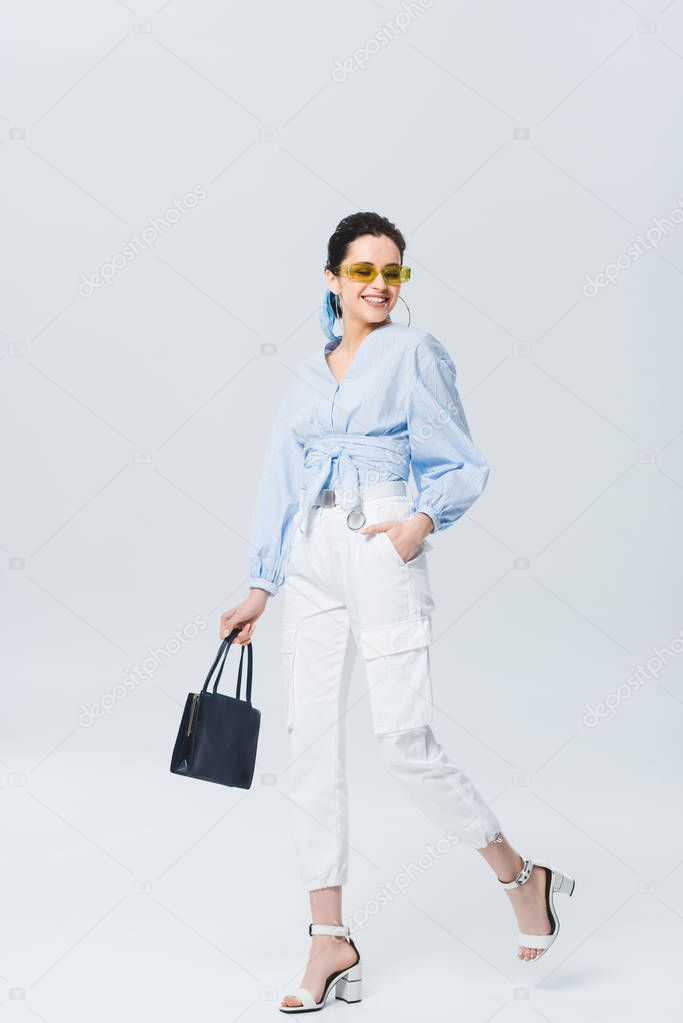 beautiful stylish girl walking and smiling on grey
