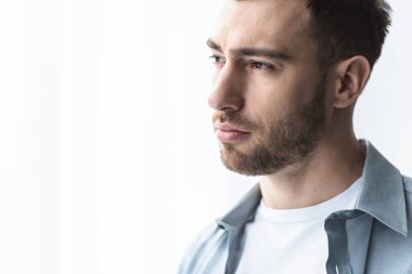 mavi gömlekli üzgün adam uzakta eve bakıyor