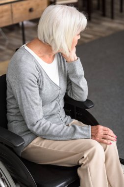 üzgün engelli yaşlı kadın tekerlekli sandalyede oturan ve uzağa bakıyor