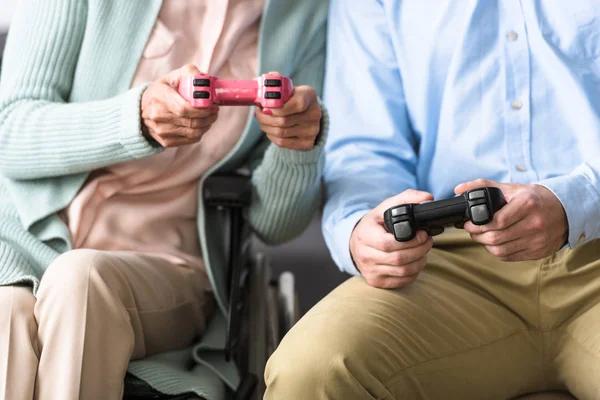 Kiev, Ukrayna - 15 Nisan 2019: yetişkin oğlu video oyunu oynarken kıdemli kadın kırpılmış atış