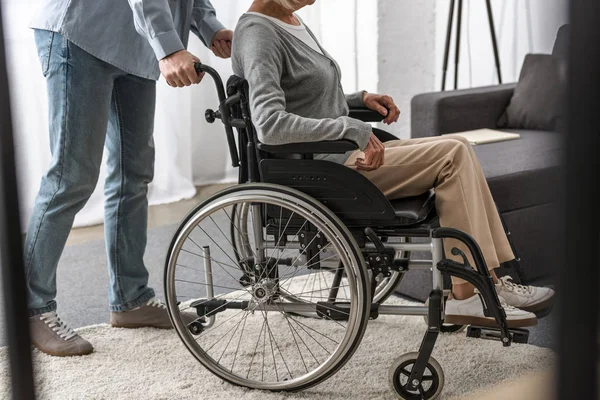 車椅子で障害のある母親を運ぶ男性のトリミングされたビュー — ストック写真