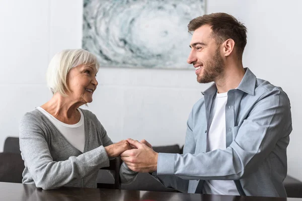 Smiling Man Holding Hands Senior Mother Home — Stock Photo, Image