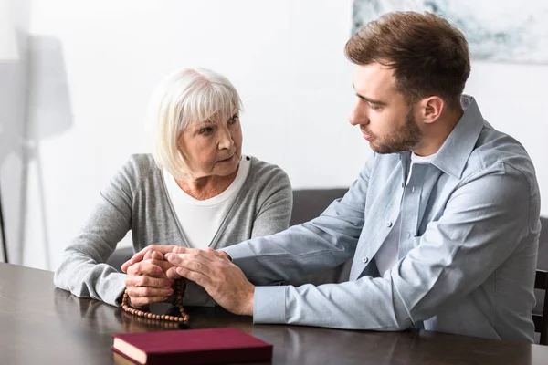 Senior Kvinna Med Radband Hålla Händer Med Son — Stockfoto