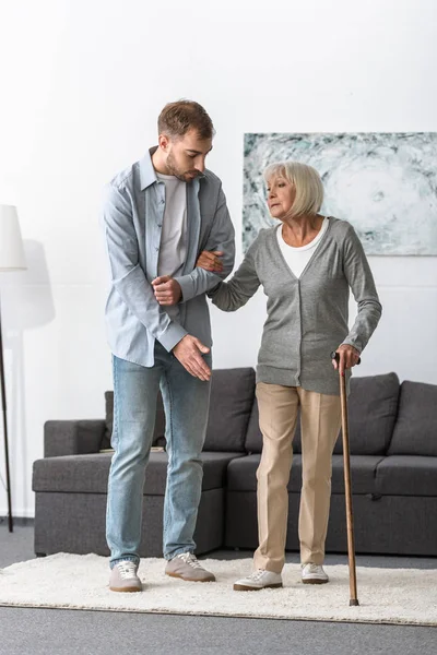 Vista Completa Del Hombre Ayudando Madre Mayor Con Bastón Casa — Foto de Stock