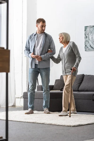 Vista Completa Del Hombre Ayudando Madre Mayor Con Bastón Casa — Foto de Stock