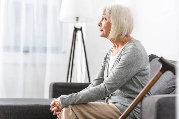 Pensive Senior Woman Wooden Cane Sitting Sofa Living Room — Stock Photo, Image