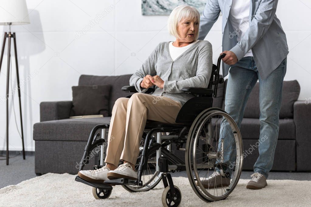 cropped view of man carrying senior mother on wheelchair