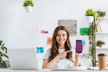Kiev, Ukrayna - 17 Nisan 2019: Ekranda Instagram uygulaması ile akıllı telefon parmak la işaret neşeli genç kadın. 