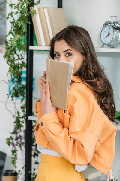 Attractive Young Woman Looking Camera While Covering Face Book — Stock Photo, Image