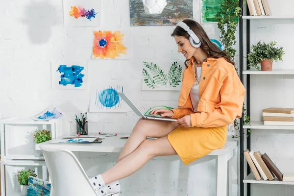 Smiling Trendy Woman Headphones Using Laptop While Sitting Desk — Stock Photo, Image