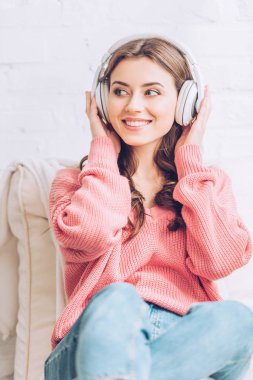 neşeli genç kadın kulaklık müzik dinleme ve uzağa bakıyor