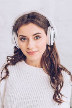 güzel genç kadın kulaklık müzik dinleme, gülümseyerek ve kamera bakarak