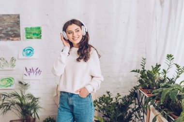 neşeli kız cepte el tutarak ve uzağa bakarken kulaklık müzik dinlerken