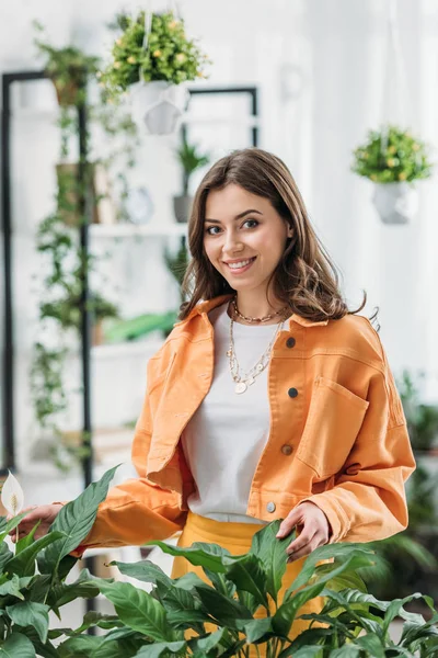 Mujer Joven Moda Sonriendo Cámara Mientras Está Pie Cerca Plantas — Foto de Stock