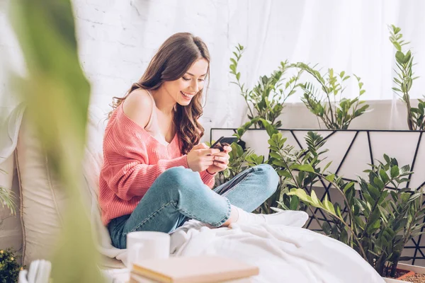 Selective Focus Cheerful Girl Using Smartphone While Sitting Crossed Legs — Stock Photo, Image