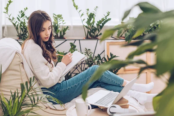 Selective Focus Attentive Young Woman Writing Using Laptop Writing Notebook — Stock Photo, Image