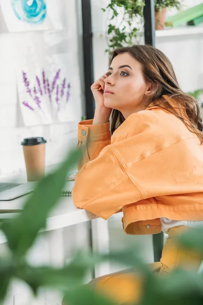 自宅の机に座っている間 目をそらすオレンジ色の閉鎖のペンシブな若い女性の選択的な焦点 — ストック写真
