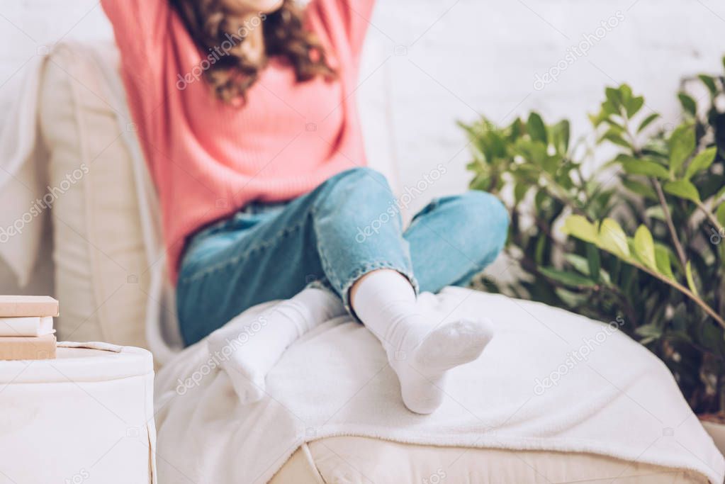 cropped view of young woman sitting on soft white chaise lounge