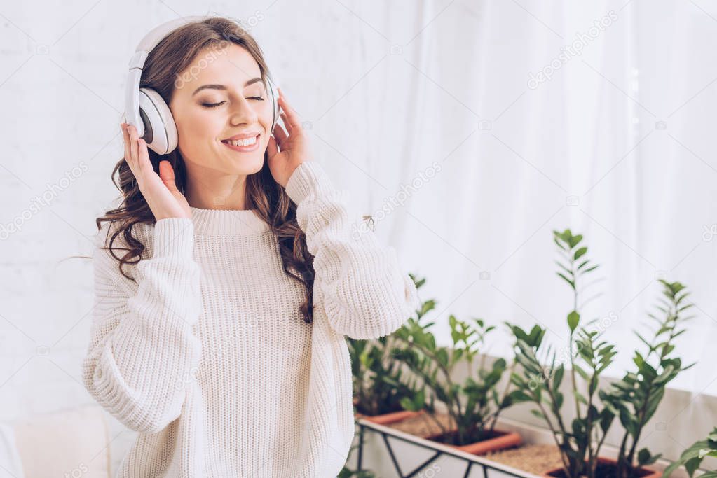 happy young woman listening music in headphones with closed eyes